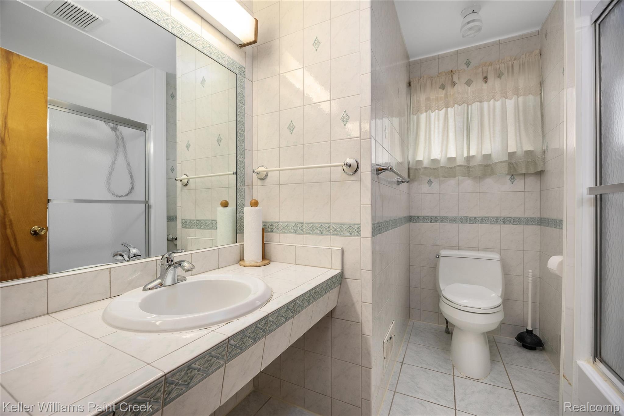 1766 Henry Ruff Road Garden City, MI 48135 - Photo 17 of 36 Bathroom featuring tile flooring, a built-in vanity with integrated sink, a large wall mirror, and a tiled shower with a sliding glass door