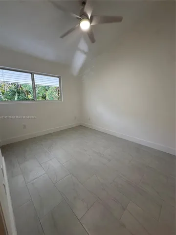 an empty room with a window and a ceiling fan