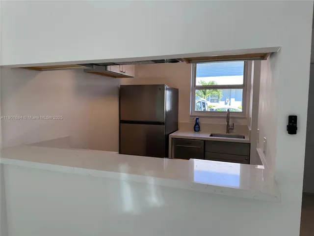 a living room with stainless steel appliances kitchen island granite countertop a refrigerator and a sink