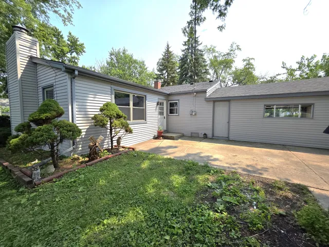 a backyard of a house with table and chairs and potted plants