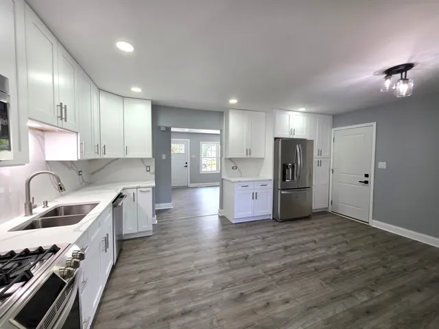 a kitchen with stainless steel appliances kitchen island granite countertop a sink stove and refrigerator