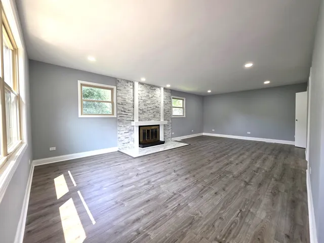 an empty room with windows fireplace and wooden floor