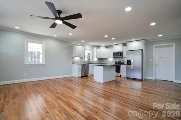 a view of kitchen with stainless steel appliances refrigerator stove and wooden floor