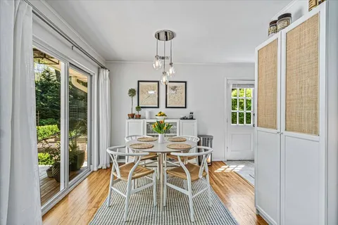 a dining room with wooden floor a chandelier a glass table and chairs