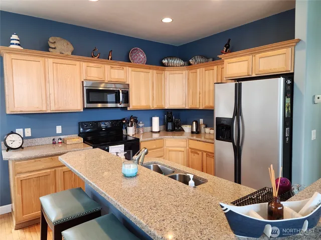 a kitchen with stainless steel appliances granite countertop a refrigerator a stove and a sink