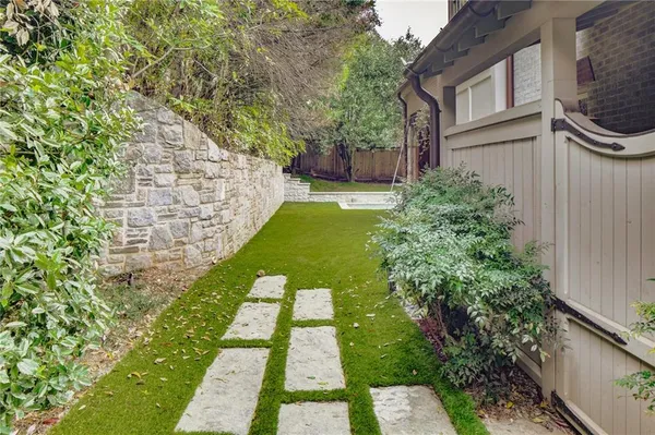 a view of a brick house with a small yard and large trees