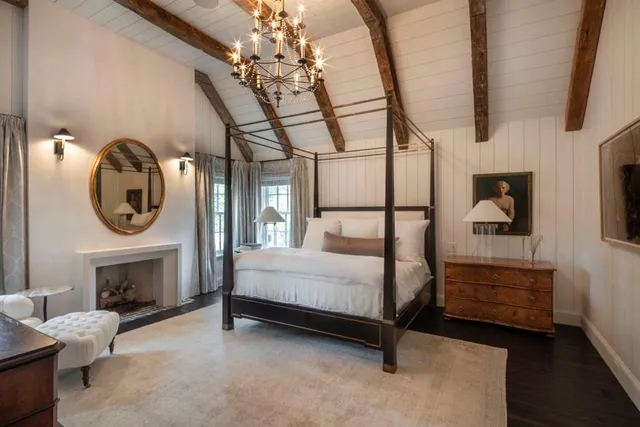 a spacious bedroom with a bed a fireplace and a chandelier