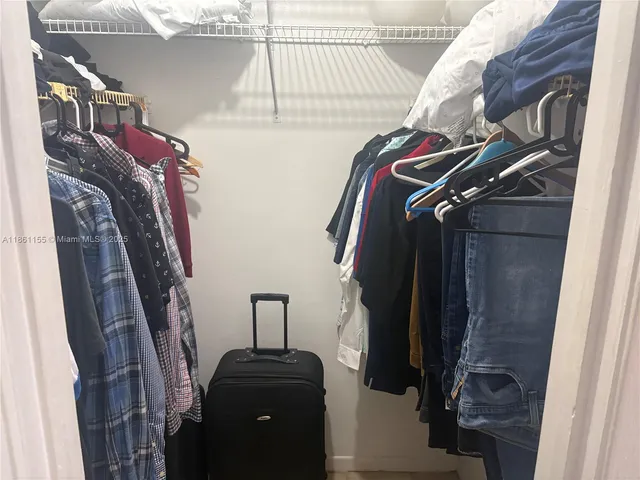 a view of walk in closet with clothes and shoes