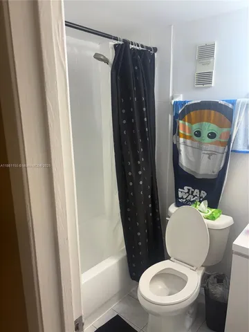 a bathroom with a toilet and a shower curtain