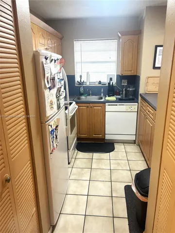 a kitchen with a sink a refrigerator a window and cabinets