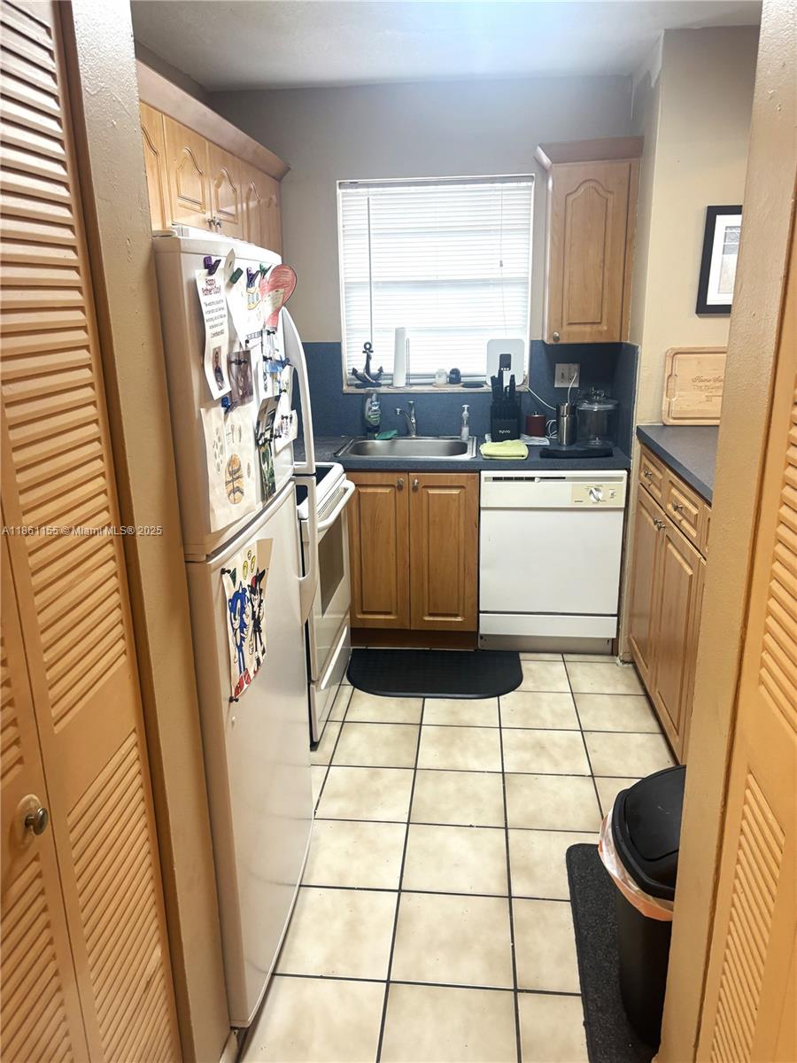 8889 Fontainebleau Boulevard, Unit 204 Miami, FL 33172 - Photo 6 of 28 a kitchen with a sink a refrigerator a window and cabinets