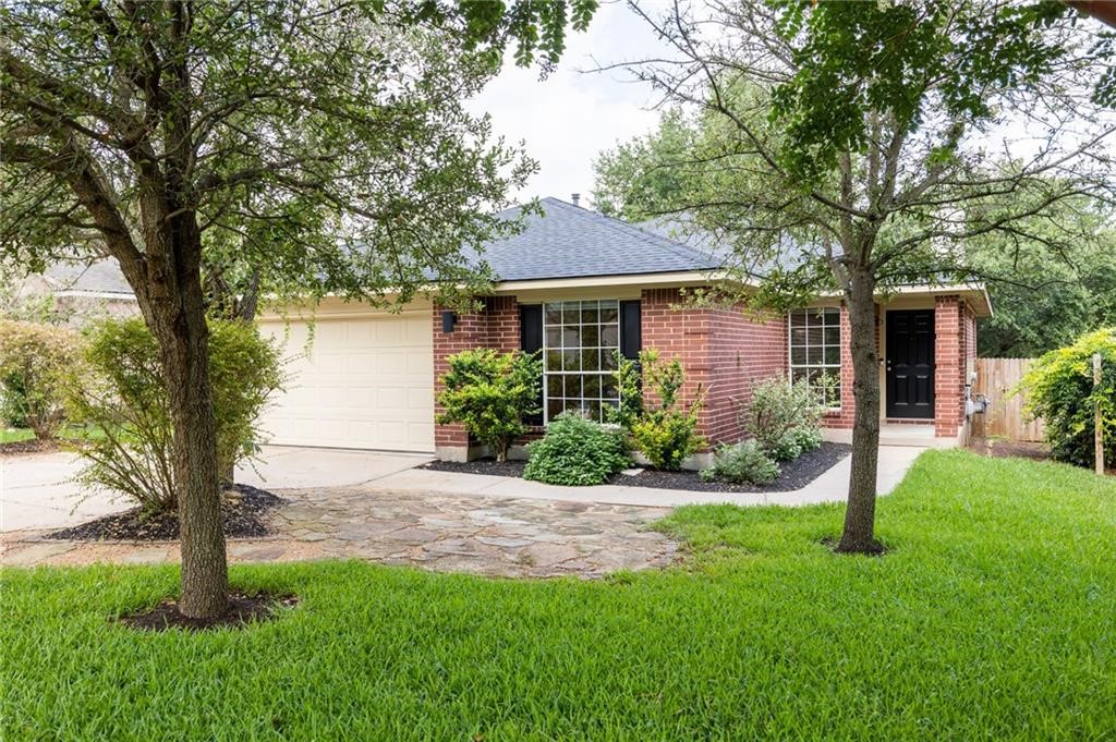 a front view of a house with a yard and tree