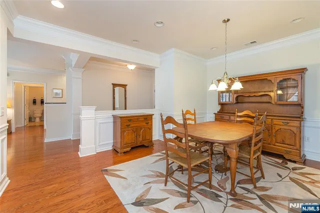 a view of a dining room and livingroom with furniture wooden floor a rug a painting and a chandelier