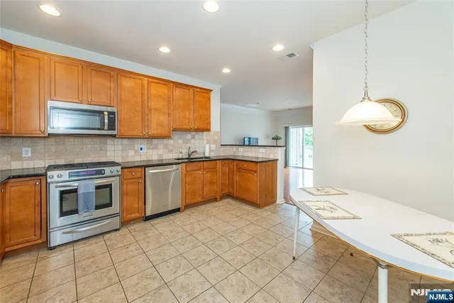 a kitchen with stainless steel appliances granite countertop a sink dishwasher stove top oven and cabinets