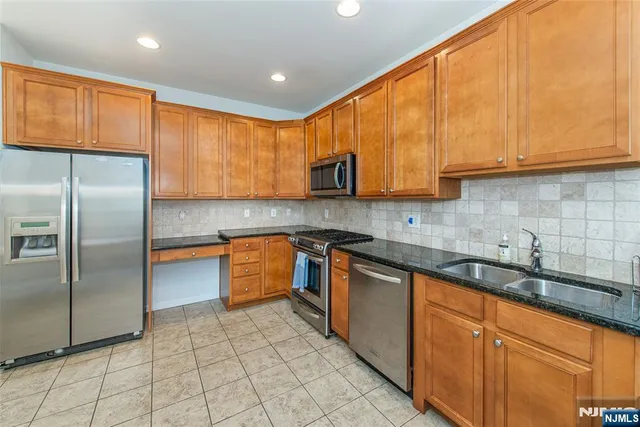 a kitchen with stainless steel appliances granite countertop a sink a stove and a refrigerator