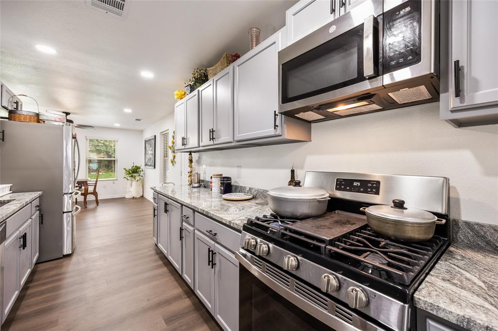 1005 Iowa Street Irving, TX 75060 - Photo 7 of 23 a kitchen with stainless steel appliances granite countertop a stove and a microwave