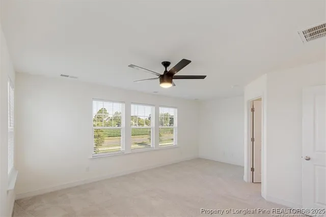 an empty room with windows and fan