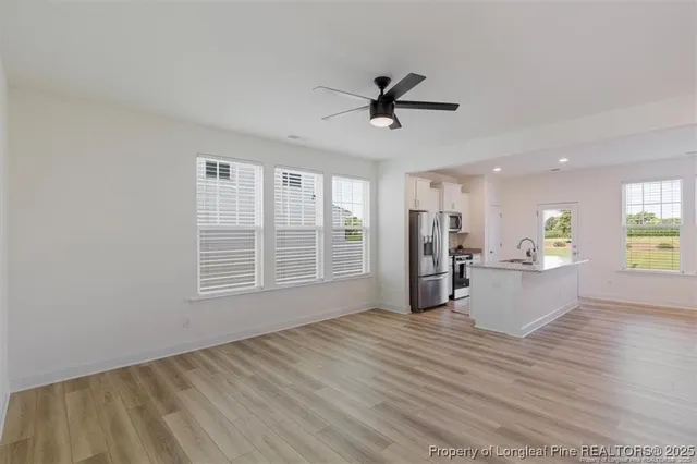 a view of an empty room with window and wooden floor