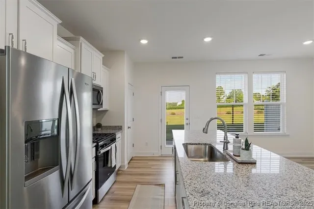 a large kitchen with a refrigerator a sink dishwasher a stove and a dining table with wooden floor