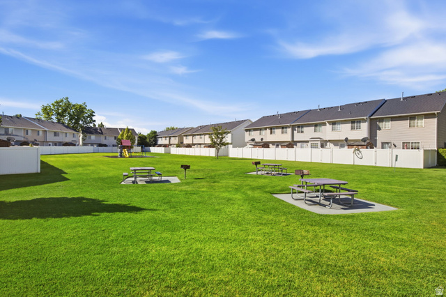 794 East 950 S Street Provo, UT 84606 - Photo 27 of 28 Expansive community green space featuring a manicured lawn, multiple picnic tables on concrete pads, built-in barbecue grills, and a dedicated play structure
