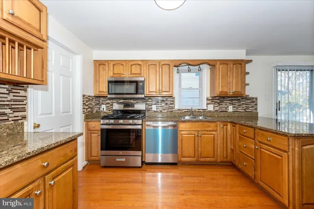 a kitchen with stainless steel appliances granite countertop a stove a sink and a microwave