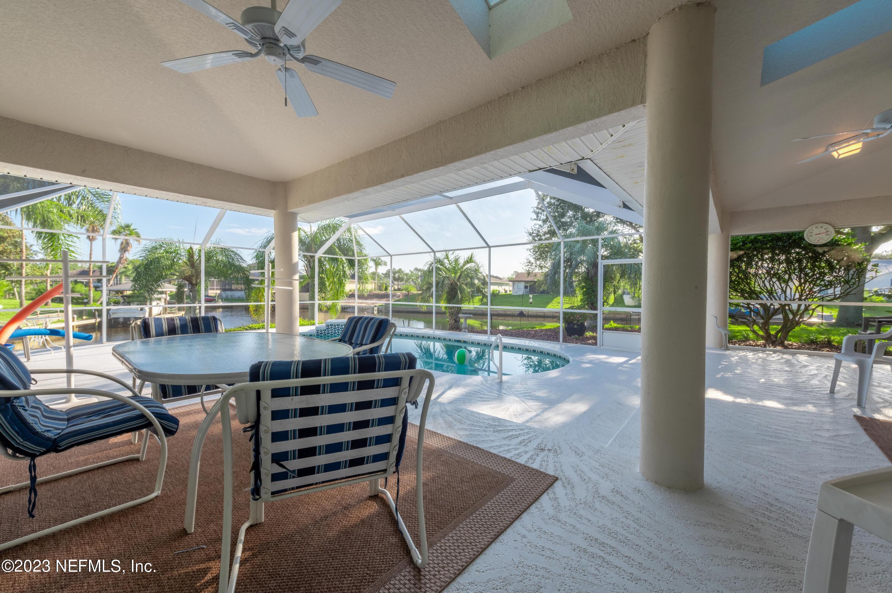 13 Clear Court Palm Coast, FL 32137 - Photo 18 of 60 a view of a patio with a table chairs and a floor to ceiling window