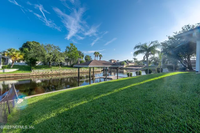 a view of a lake with a yard and large trees