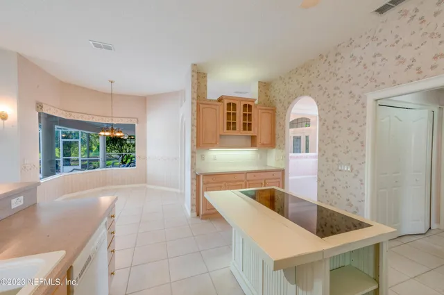 an empty room with a chandelier fan and windows