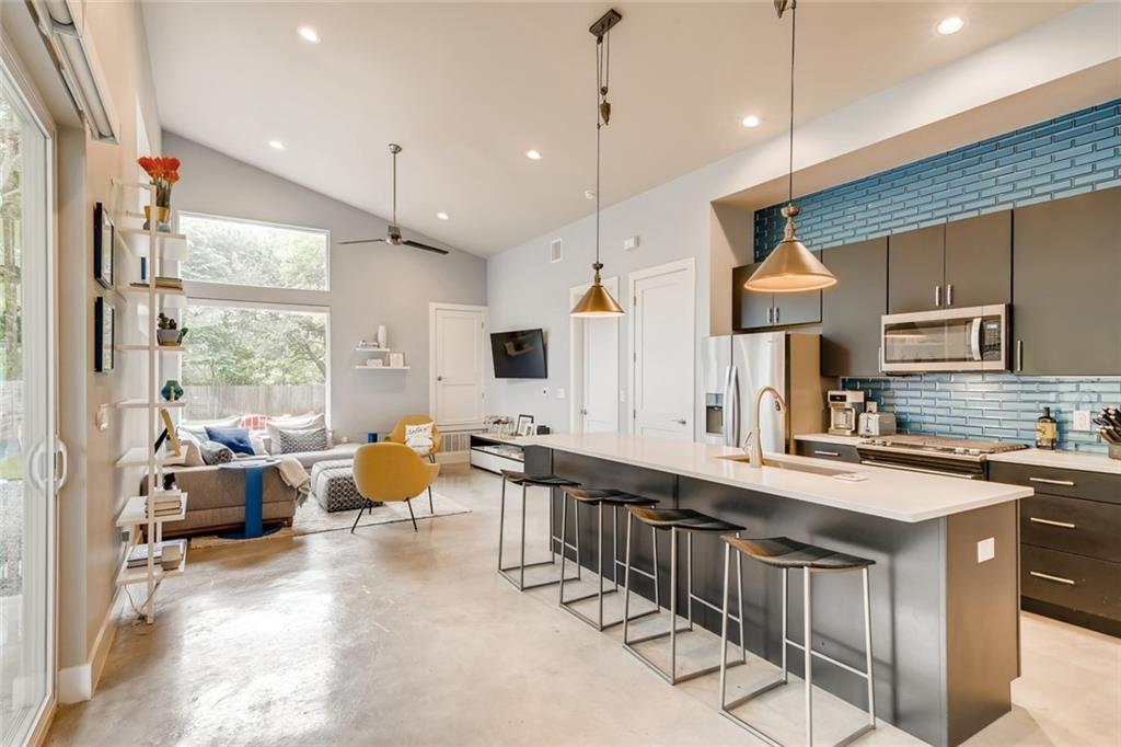1142 Eleanor Street, Unit 2 Austin, TX 78721 - Photo 4 of 24 An open concept living area boasts a modern kitchen island, recessed lighting, and expansive windows.
