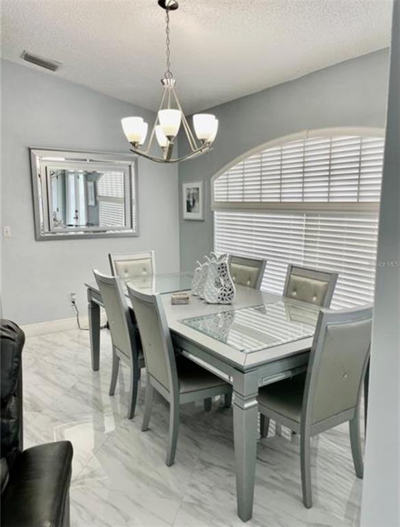 6125 Mariner Boulevard Spring Hill, FL 34608 - Photo 6 of 24 a view of a dining room with furniture a chandelier and wooden floor