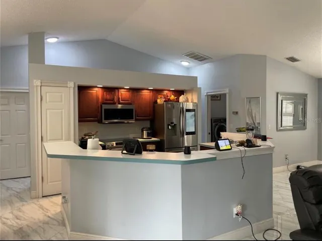 a room with stainless steel appliances a sink and a flat screen tv
