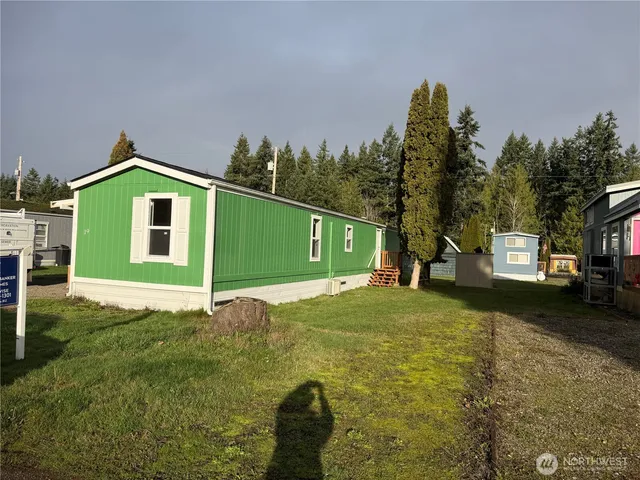 a yellow and red brick house with a big yard and large trees