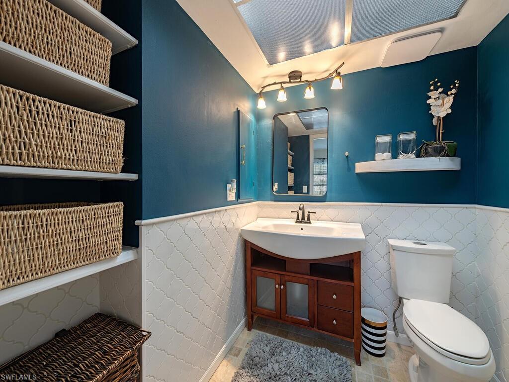 39 Watercolor Way, Unit 39 Naples, FL 34113 - Photo 7 of 12 Bathroom with toilet, tile patterned flooring, a wainscoted wall, and vanity