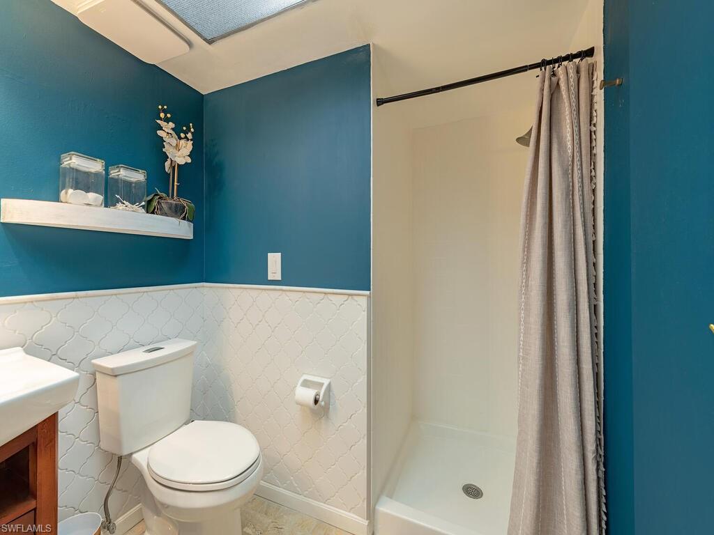39 Watercolor Way, Unit 39 Naples, FL 34113 - Photo 8 of 12 Full bath with tile walls, toilet, a shower stall, wainscoting, and vanity