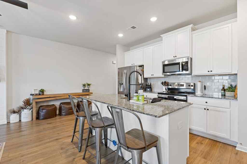 60 Huntley Trace Hoschton, GA 30548 - Photo 7 of 50 a kitchen with stainless steel appliances granite countertop a stove a sink a microwave a refrigerator with a dining table and chairs