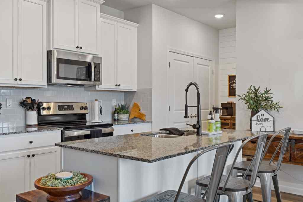 60 Huntley Trace Hoschton, GA 30548 - Photo 8 of 50 a kitchen with stainless steel appliances granite countertop a stove a sink dishwasher and white cabinets with wooden floor