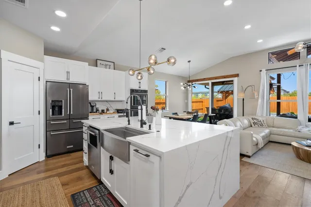 a kitchen with stainless steel appliances a refrigerator a stove a sink dishwasher and white cabinets with wooden floor