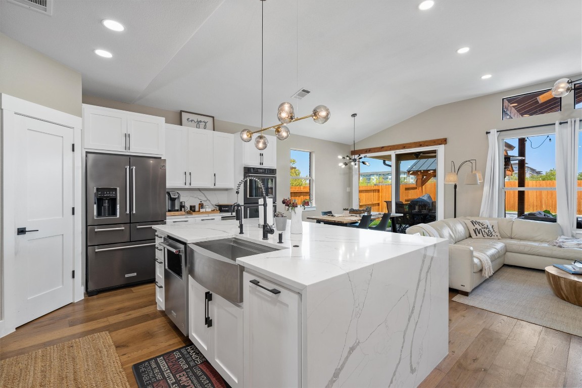 542 Centerbrook Place Round Rock, TX 78665 - Photo 8 of 40 a kitchen with stainless steel appliances a refrigerator a stove a sink dishwasher and white cabinets with wooden floor