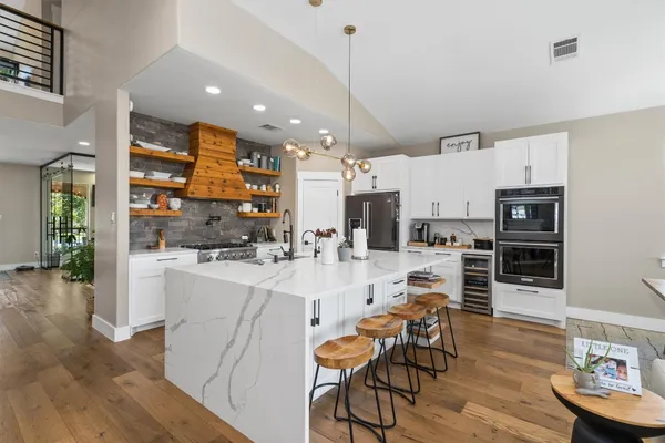 a kitchen with stainless steel appliances kitchen island granite countertop a table chairs and a refrigerator