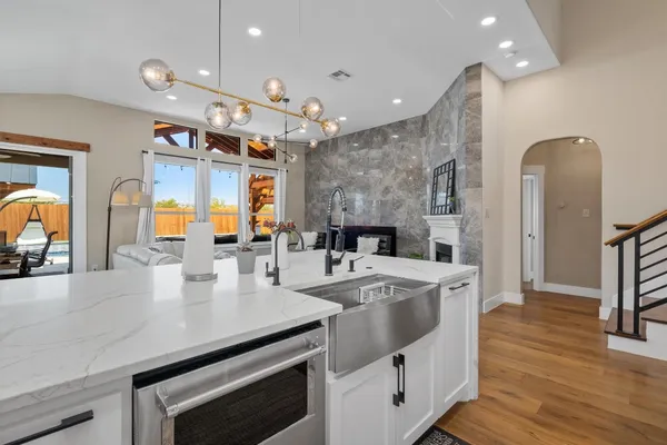 a large kitchen with stainless steel appliances a large counter top a stove and a sink