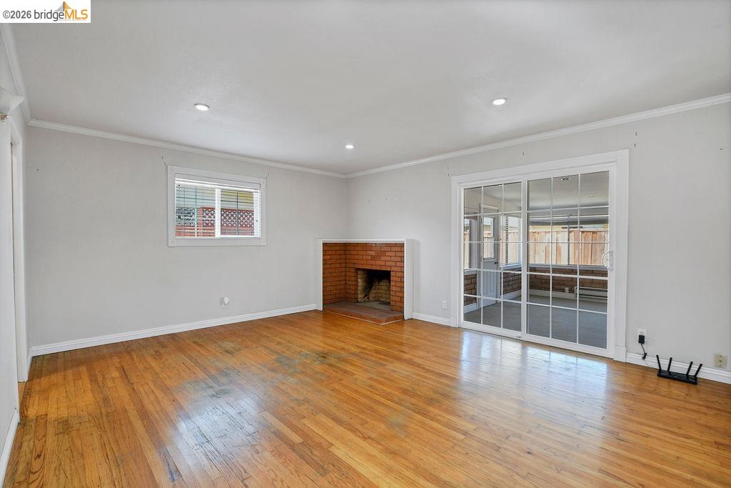 805 Calero Street Milpitas, CA 95035 - Photo 4 of 23 Bright interior with wood-finish flooring, a brick fireplace, a window with horizontal blinds, and sliding glass doors featuring multiple panes