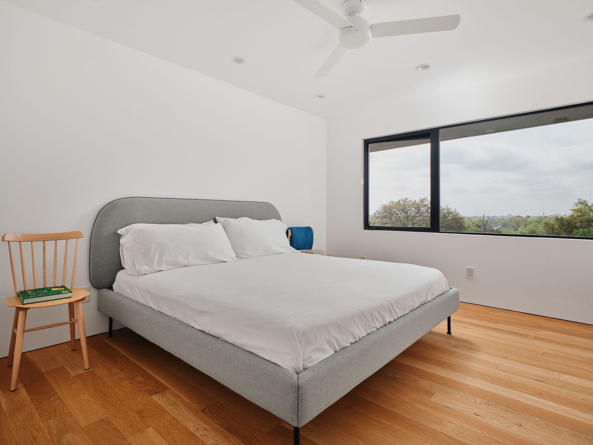 Undisclosed Address Austin, TX 78731 - Photo 13 of 26 Hardwood flooring extends through this airy bedroom, complemented by a broad window offering expansive outdoor views.