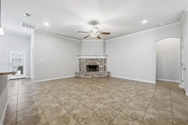 an empty room with a fireplace and chandelier fan