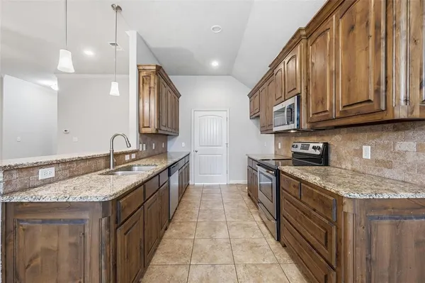 a kitchen with stainless steel appliances granite countertop a stove a sink and a microwave