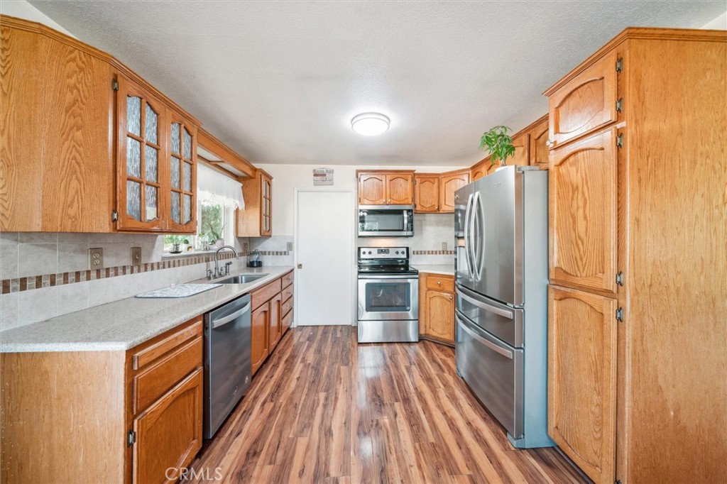 6791 Whispering Canyon Drive Anderson, CA 96007 - Photo 11 of 51 a kitchen with stainless steel appliances granite countertop a refrigerator a stove a sink and dishwasher with wooden floor