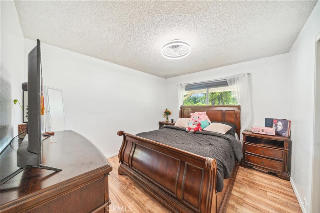 6791 Whispering Canyon Drive Anderson, CA 96007 - Photo 16 of 51 a bedroom with a bed and a table with wooden floor