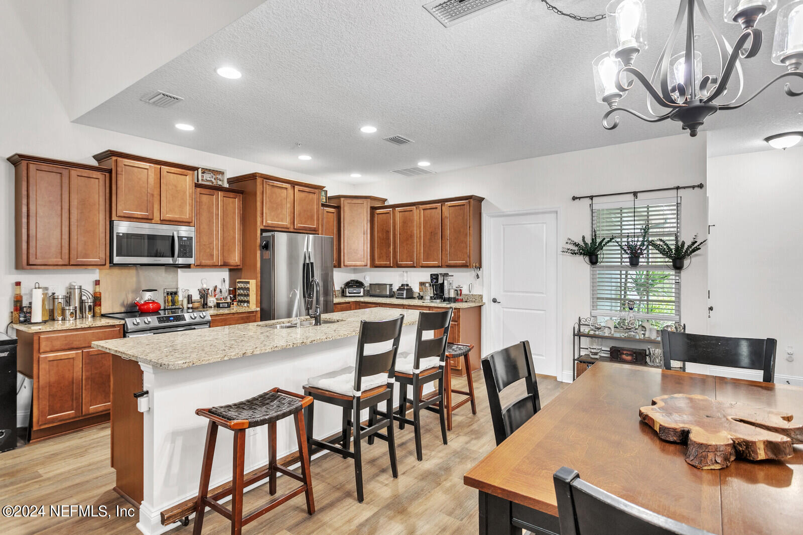4190 Quiet Crk Loop Middleburg, FL 32068 - Photo 7 of 22 a kitchen with stainless steel appliances granite countertop a stove top oven a sink a dining table and chairs with wooden floor