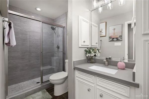 a bathroom with a granite countertop sink a toilet and shower