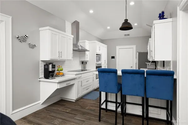 a kitchen with stainless steel appliances granite countertop a sink a stove a refrigerator and island with wooden floor