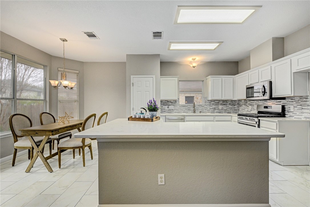 3504 Texas Topaz Drive Austin, TX 78728 - Photo 11 of 29 a kitchen with kitchen island a sink table and chairs